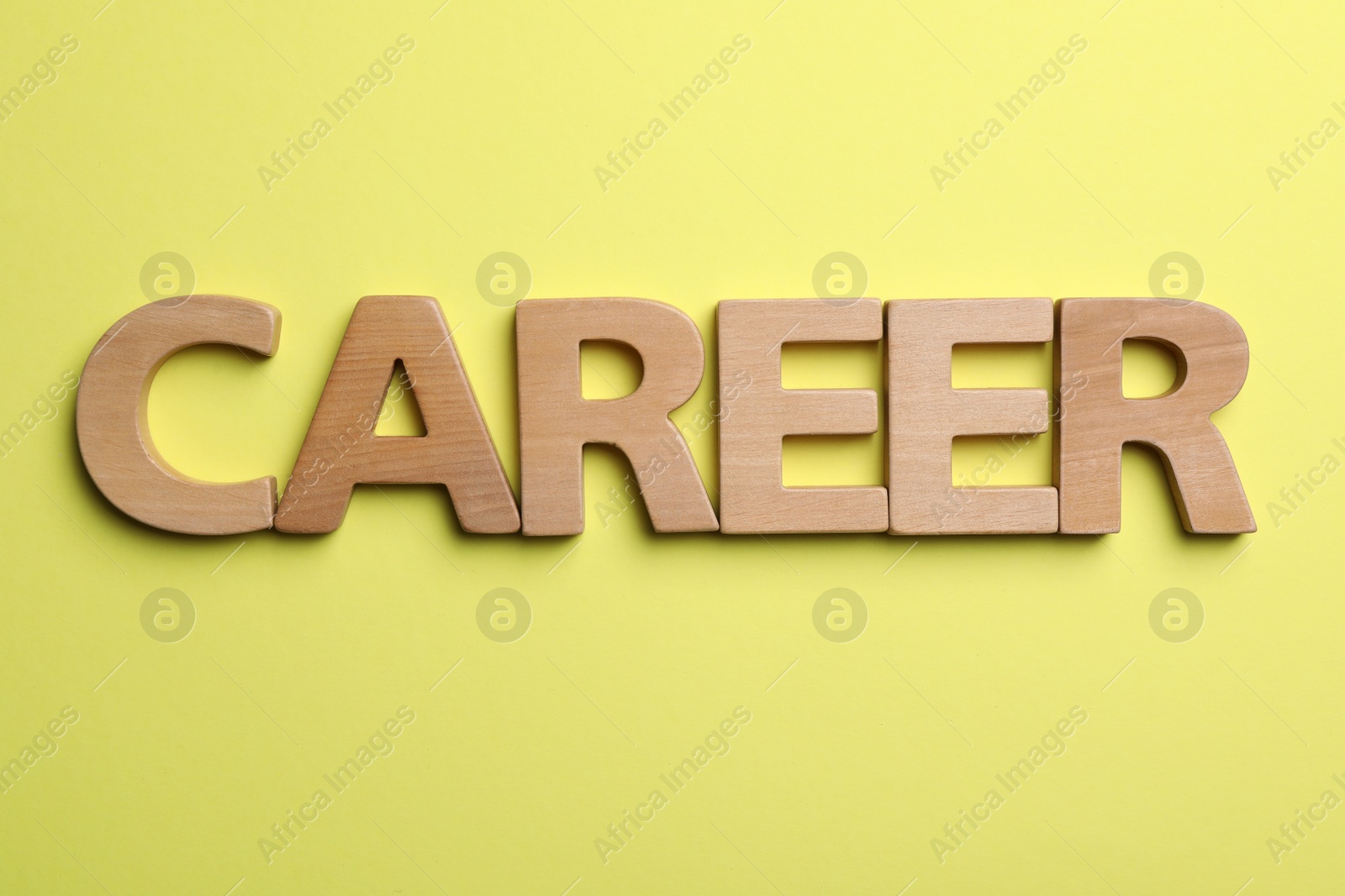 Photo of Word CAREER made with wooden letters on yellow background, flat lay