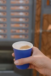 Photo of Woman holding paper cup with coffee near vending machine, closeup