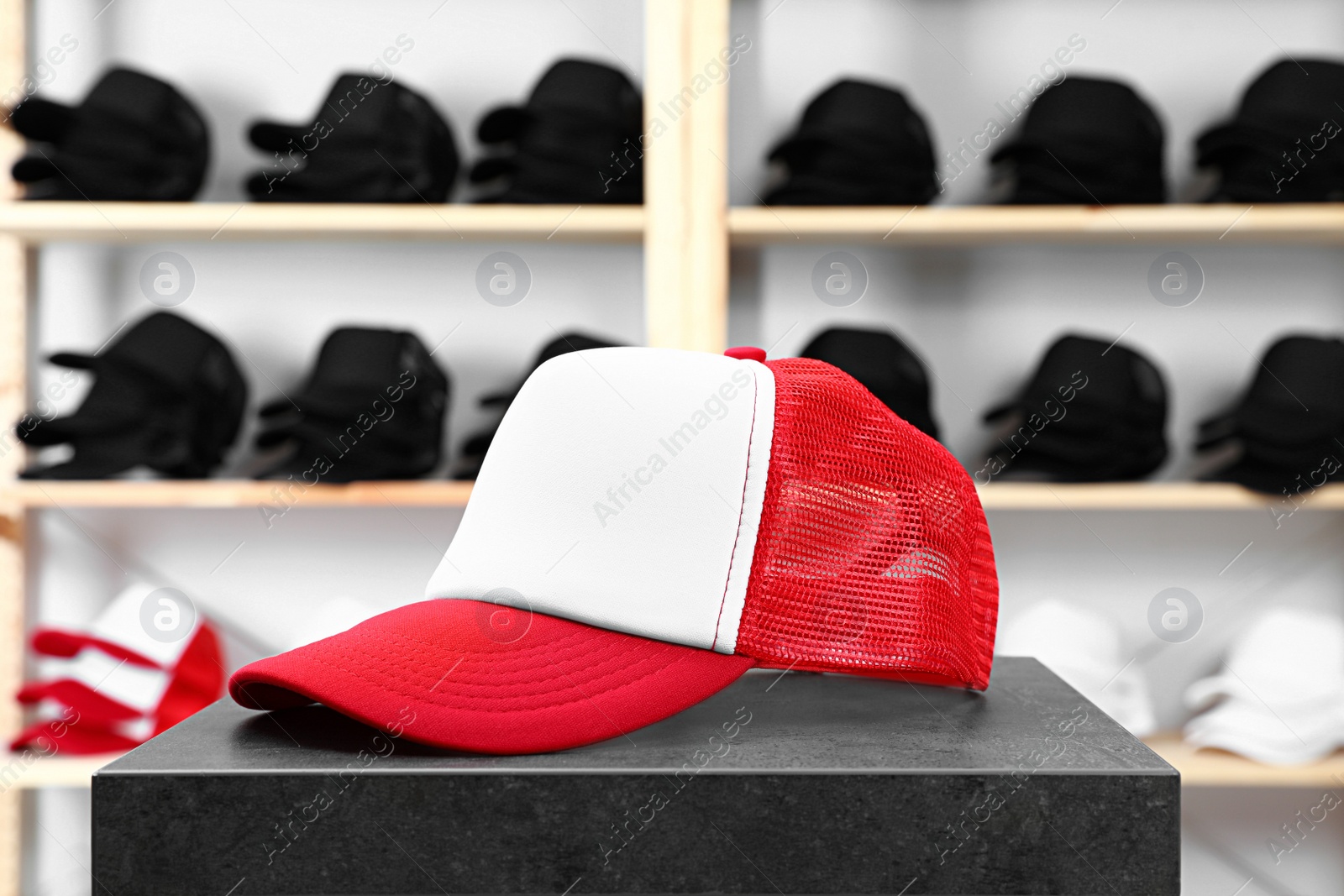 Photo of Blank red and white cap on black table in store. Mock up for design