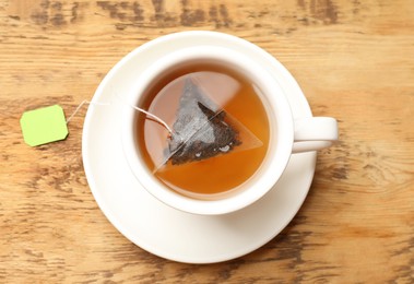 Photo of Tea bag in cup on wooden table, top view