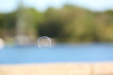 Photo of Beautiful translucent soap bubble outdoors on sunny day. Space for text