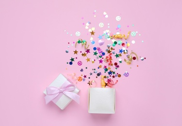 Photo of Shiny colorful confetti bursting out of box on pink background, top view