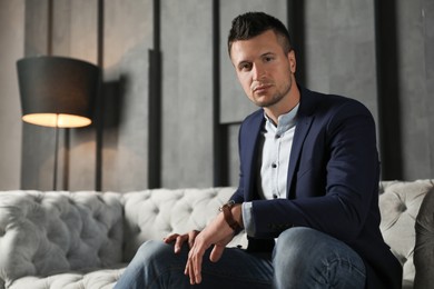 Handsome businessman on sofa indoors. Luxury lifestyle