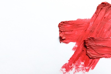 Photo of Red lipstick smear on white background, top view. Space for text