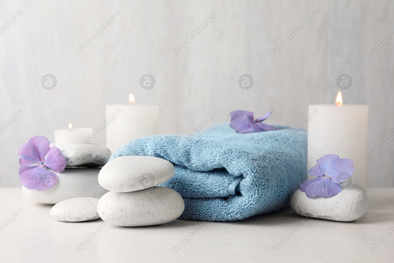 Photo of Composition with zen stones, towel and candles on table against light background