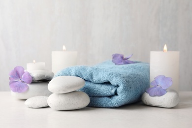 Photo of Composition with zen stones, towel and candles on table against light background