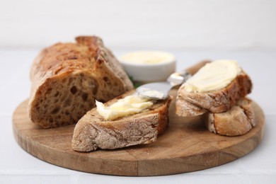 Photo of Tasty bread with butter and knife on white tiled table, closeup. Space for text