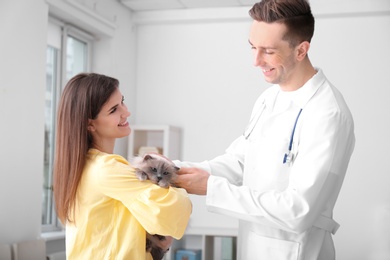 Photo of Young woman with cat and veterinarian in clinic