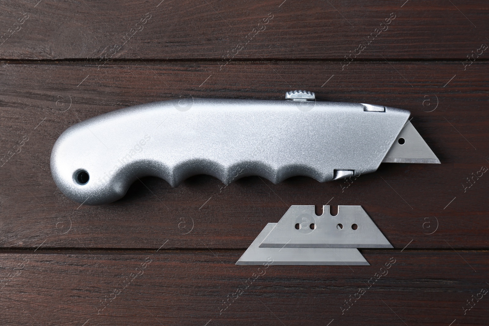 Photo of Utility knife and blades on wooden table, flat lay