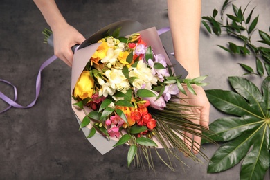 Photo of Woman with beautiful bouquet of freesia flowers on grey background