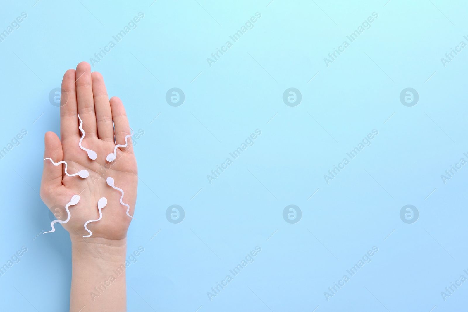 Photo of Reproductive medicine. Woman holding figures of sperm cells on light blue background, top view with space for text