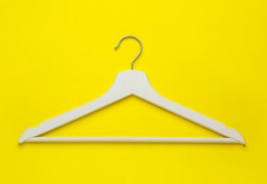 Photo of Empty wooden hanger on yellow background, top view