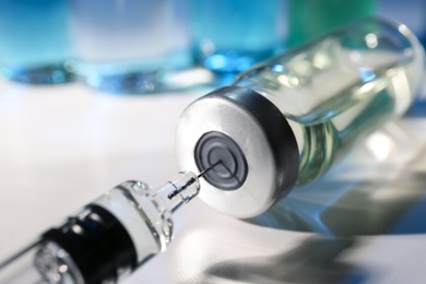 Filling syringe with vaccine from vial on table, closeup