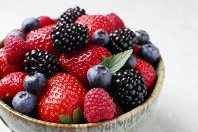 Photo of Different fresh ripe berries in bowl on table, closeup