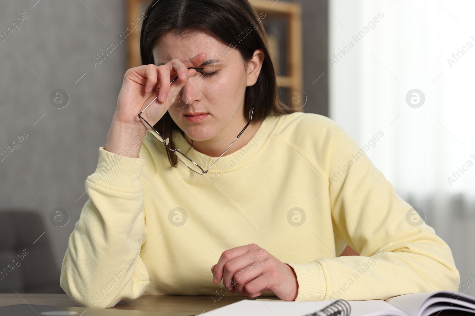 Photo of Overwhelmed woman with glasses at table indoors