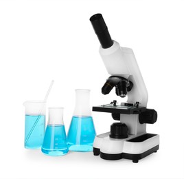 Photo of Laboratory glassware with light blue liquid and microscope isolated on white