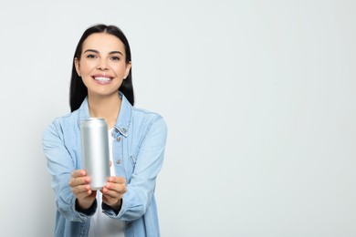 Photo of Beautiful happy woman holding beverage can on light grey background. Space for text