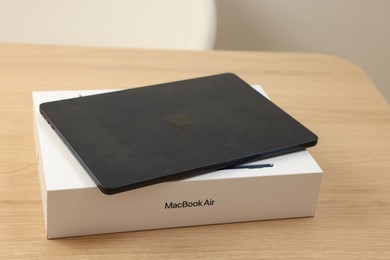 Photo of Leiden, Netherlands - October 6, 2023: Modern black MacBook Air and box on wooden table