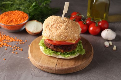 Board with delicious vegetarian burger on grey textured table