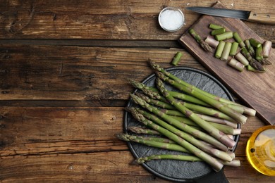 Fresh raw asparagus on wooden table, flat lay. Space for text