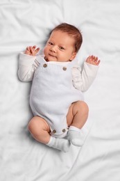 Photo of Cute newborn baby lying on white blanket, top view