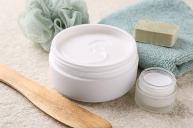 Photo of Body care cream in open jars on light textured table, closeup