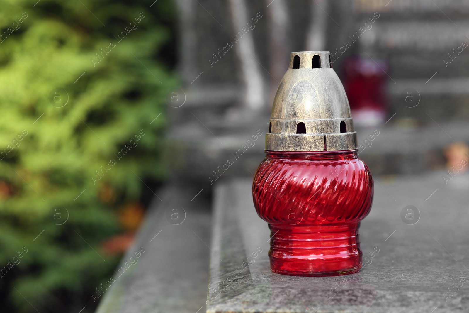 Photo of Red grave lantern with burning candle on granite surface in cemetery, space for text