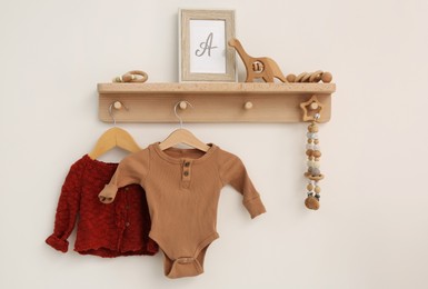 Wooden shelf with baby clothes, toys and accessories in room. Interior design