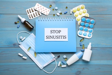 Photo of Notebook with word SINUSITIS, medical mask and different drugs on light blue wooden background, flat lay