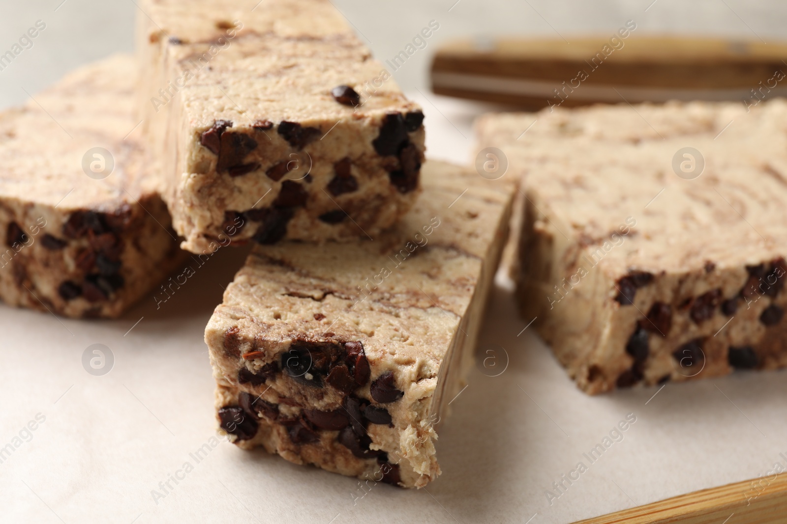 Photo of Pieces of tasty chocolate halva on board, closeup