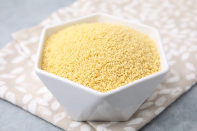 Photo of Raw couscous in bowl on table, closeup