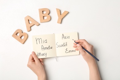 Photo of Woman choosing baby name at white table, top view