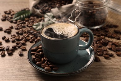 Image of Cup of aromatic hot coffee and beans on wooden table