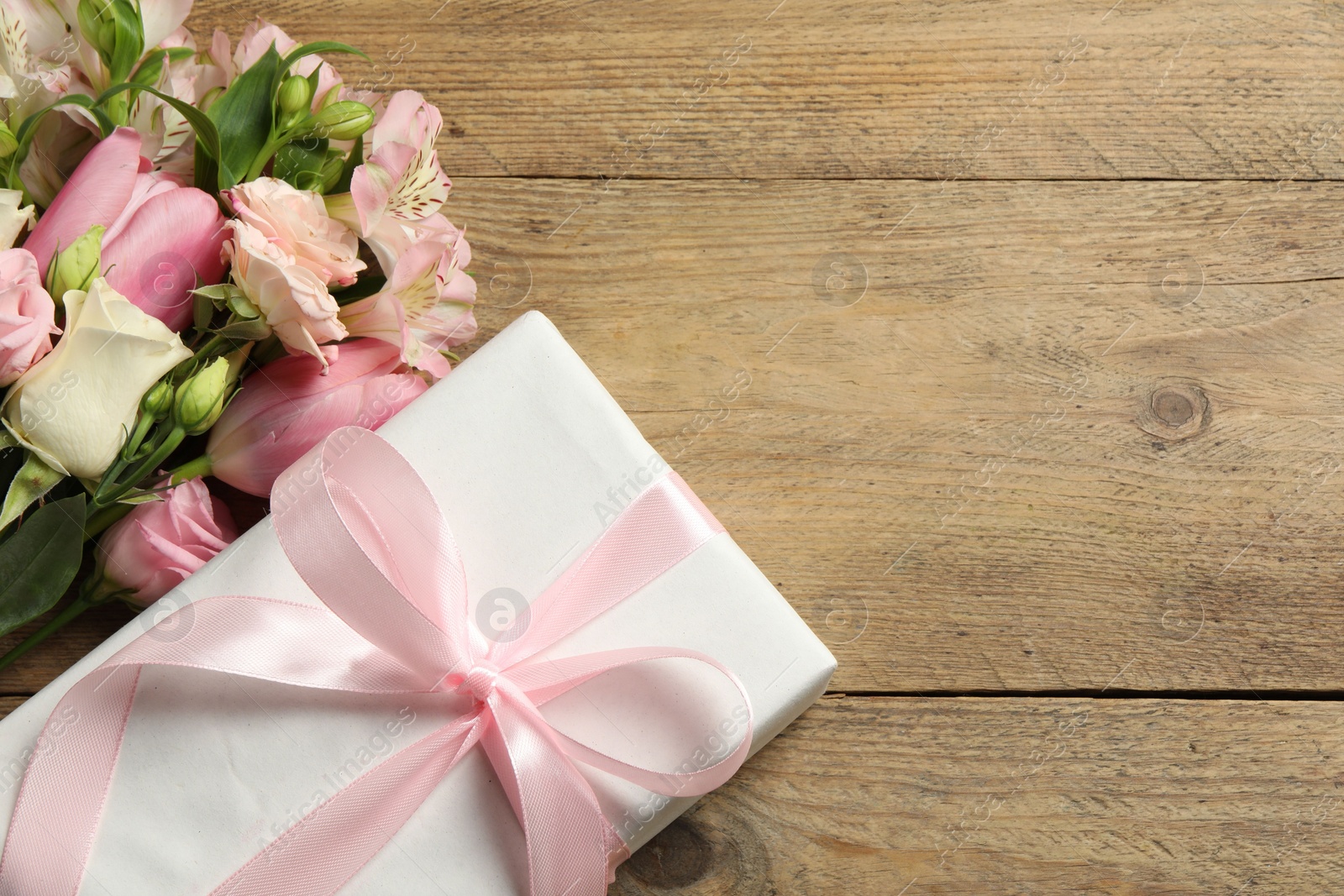 Photo of Happy Mother's Day. Beautiful flowers and gift box on wooden table, flat lay. Space for text