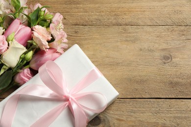 Happy Mother's Day. Beautiful flowers and gift box on wooden table, flat lay. Space for text