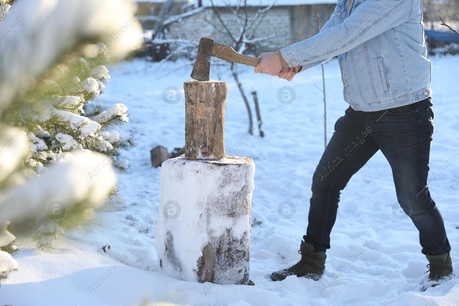 Photo of Man chopping wood with axe outdoors on winter day, closeup