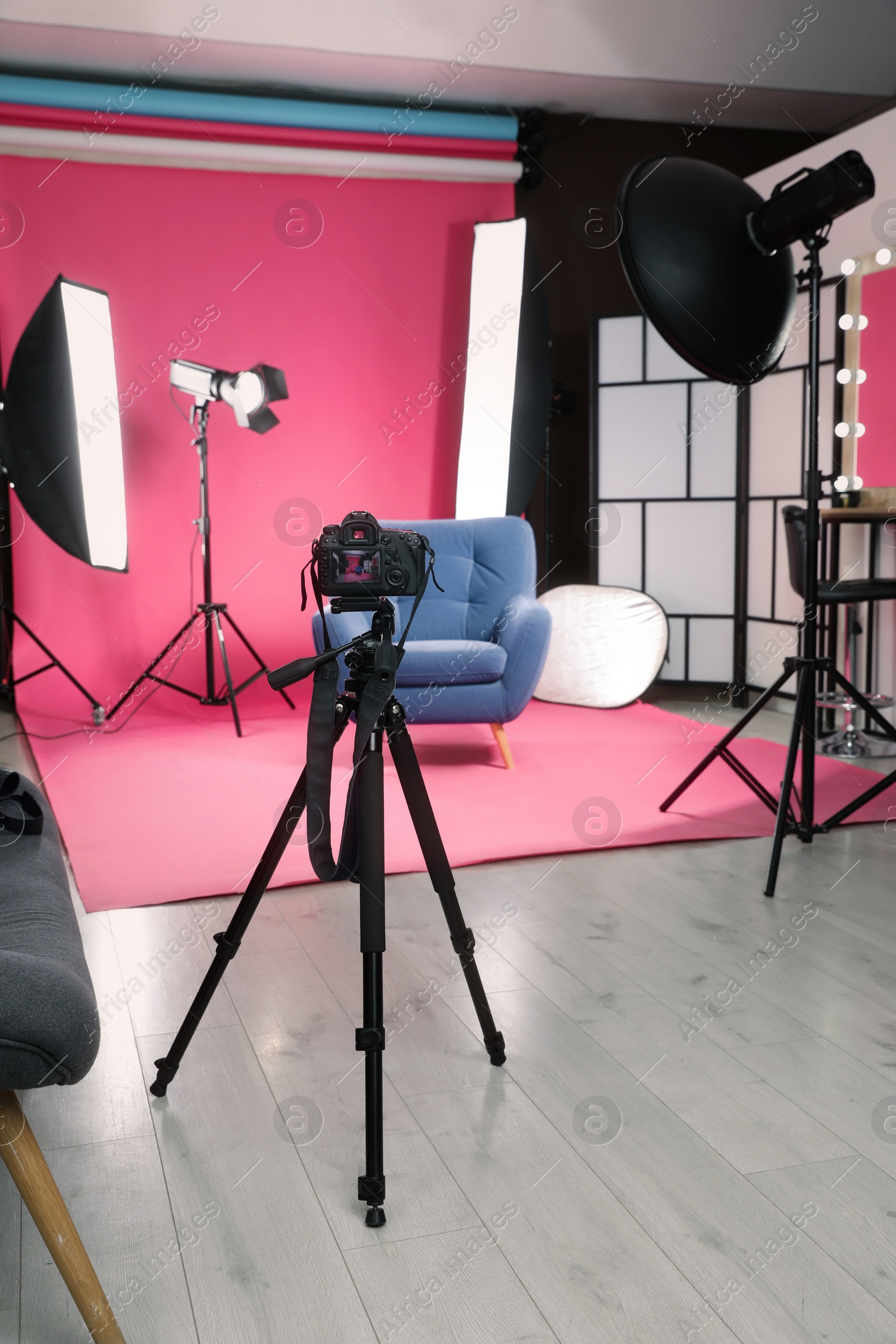 Photo of Stylish blue armchair in photo studio with professional equipment