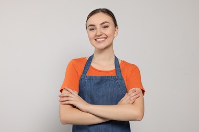 Beautiful young woman in clean denim apron on light grey background