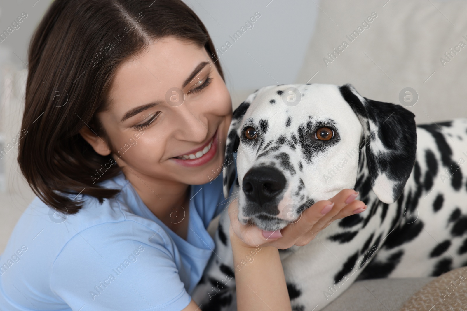 Photo of Beautiful woman with her adorable Dalmatian dog indoors. Lovely pet