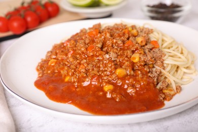 Tasty dish with fried minced meat, spaghetti, carrot and corn served on white textured table, closeup