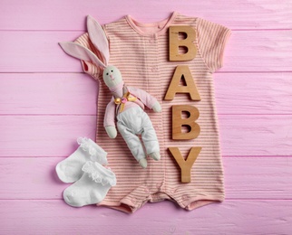 Photo of Flat lay composition with cute clothes on wooden background. Baby accessories