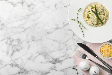 Photo of Delicious risotto with asparagus served on marble table, flat lay. Space for text