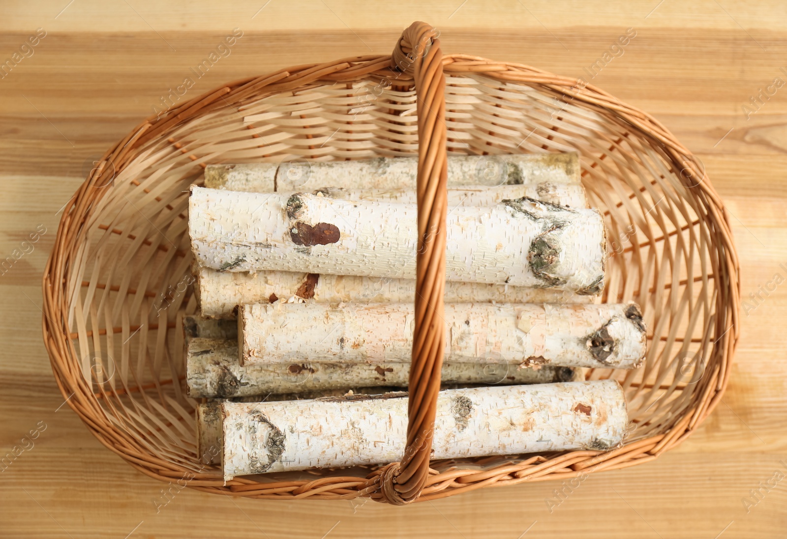 Photo of Wicker basket with firewood on floor indoors, top view