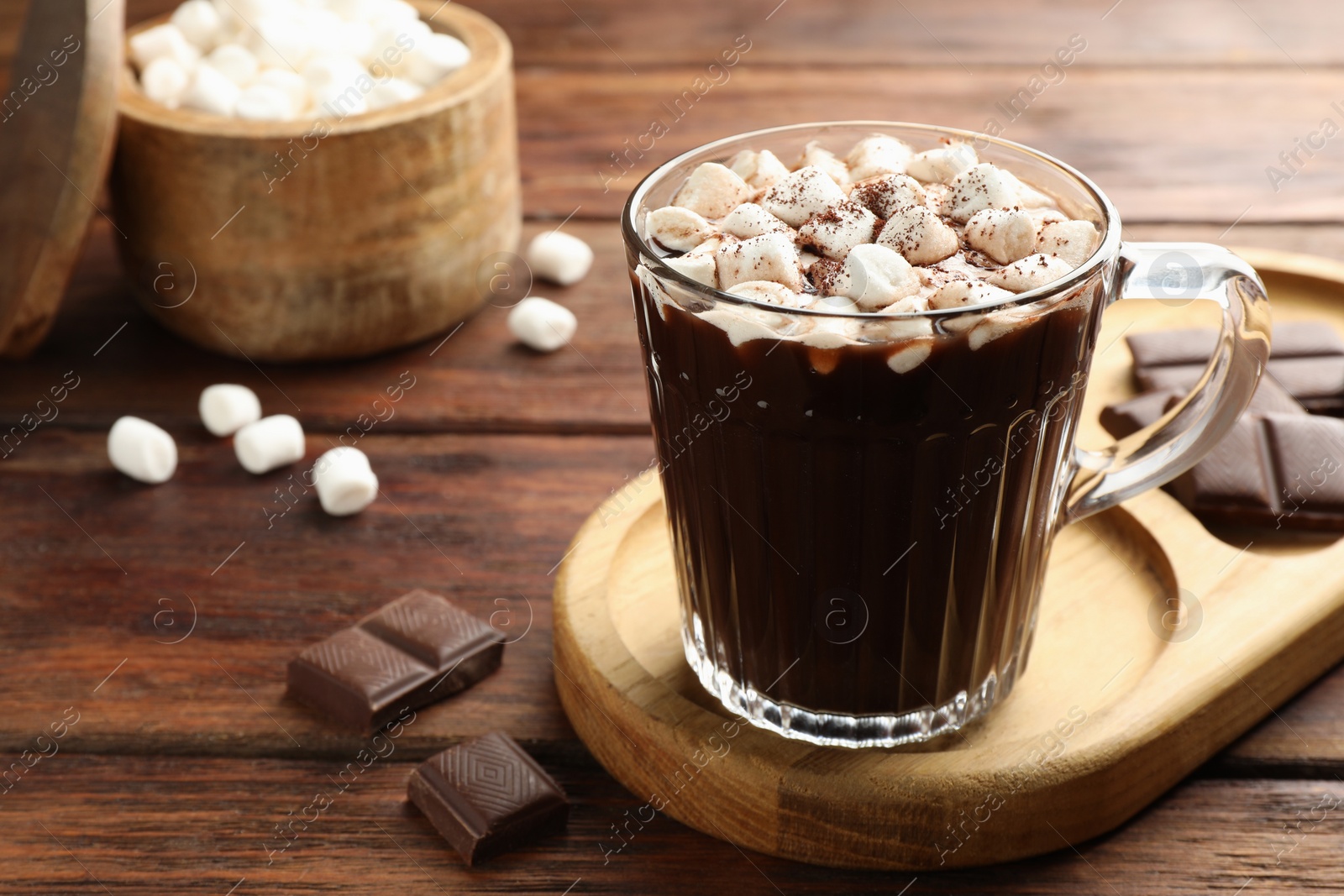 Photo of Cup of aromatic hot chocolate with marshmallows and cocoa powder served on wooden table, closeup