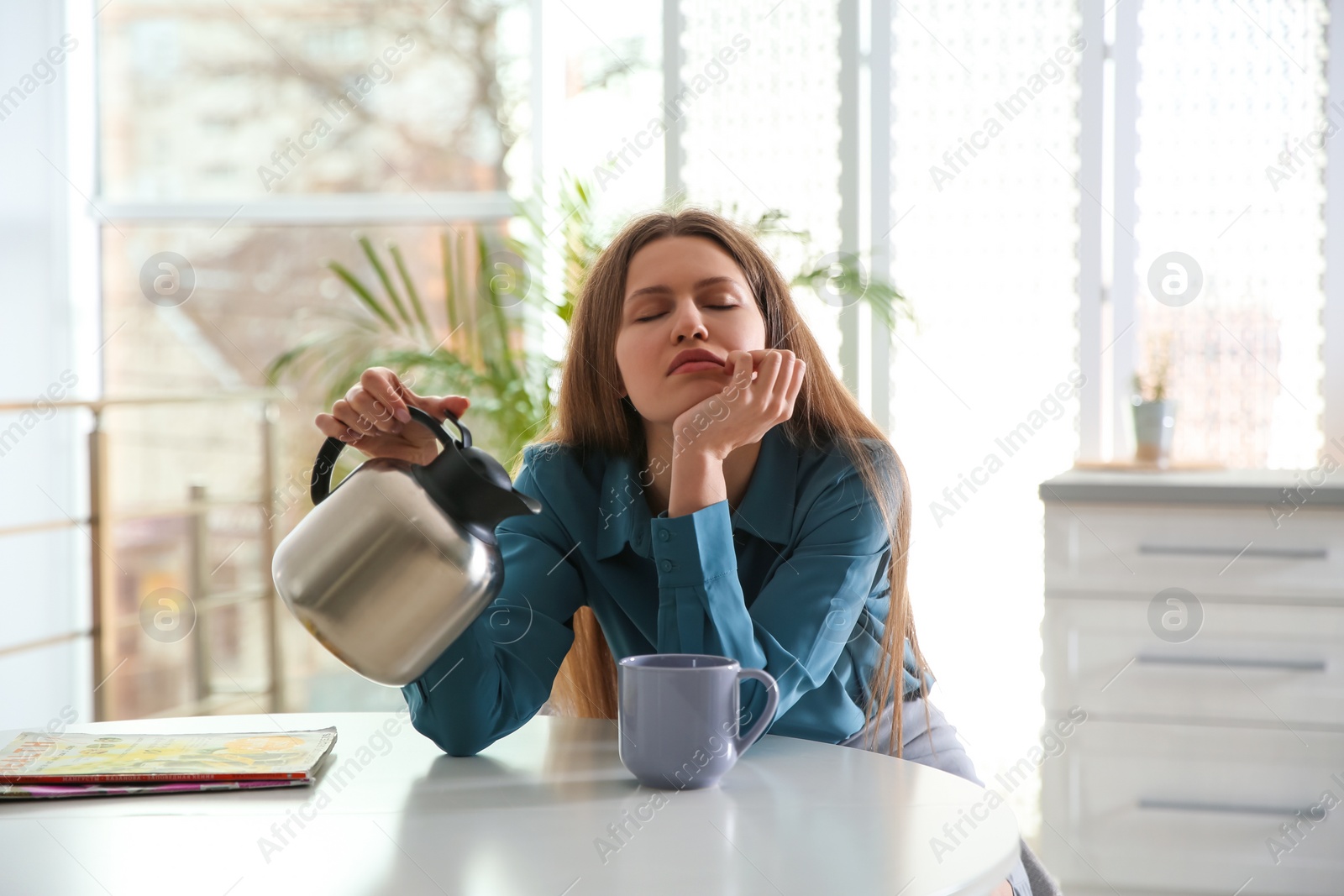 Photo of Sleepy young woman pouring coffee into cup at home in morning