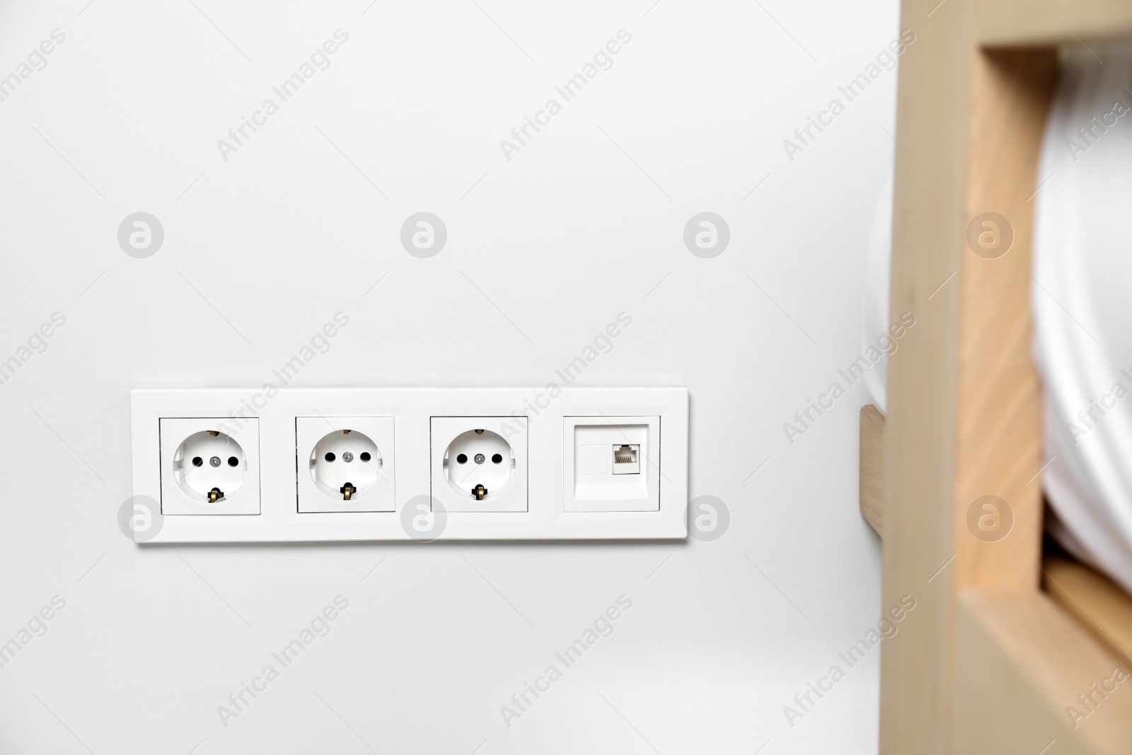 Photo of Power sockets on white wall indoors. Electrical supply