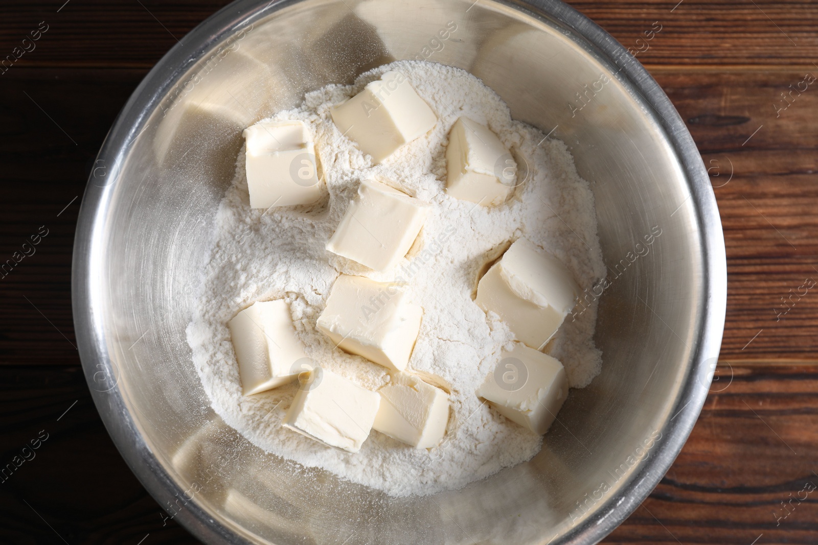 Photo of Making shortcrust pastry. Flour and butter in bowl on wooden table, top view