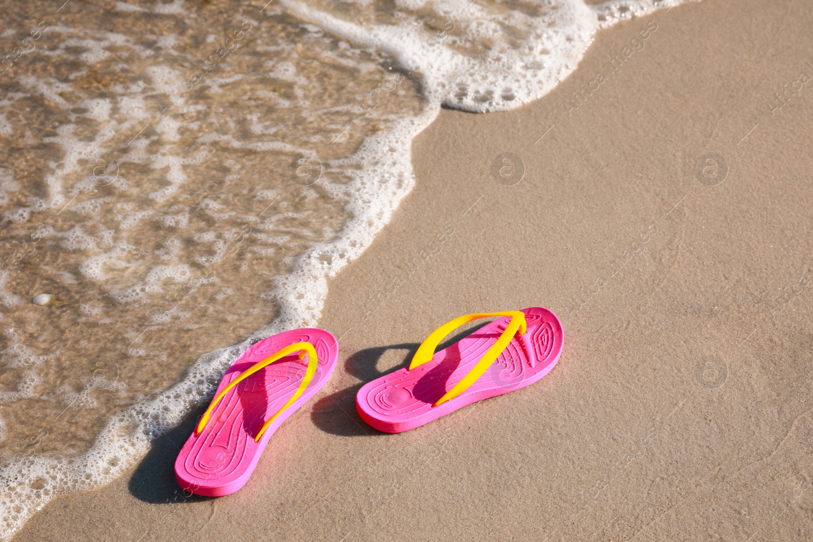 Photo of Pair of stylish flip flops on beach