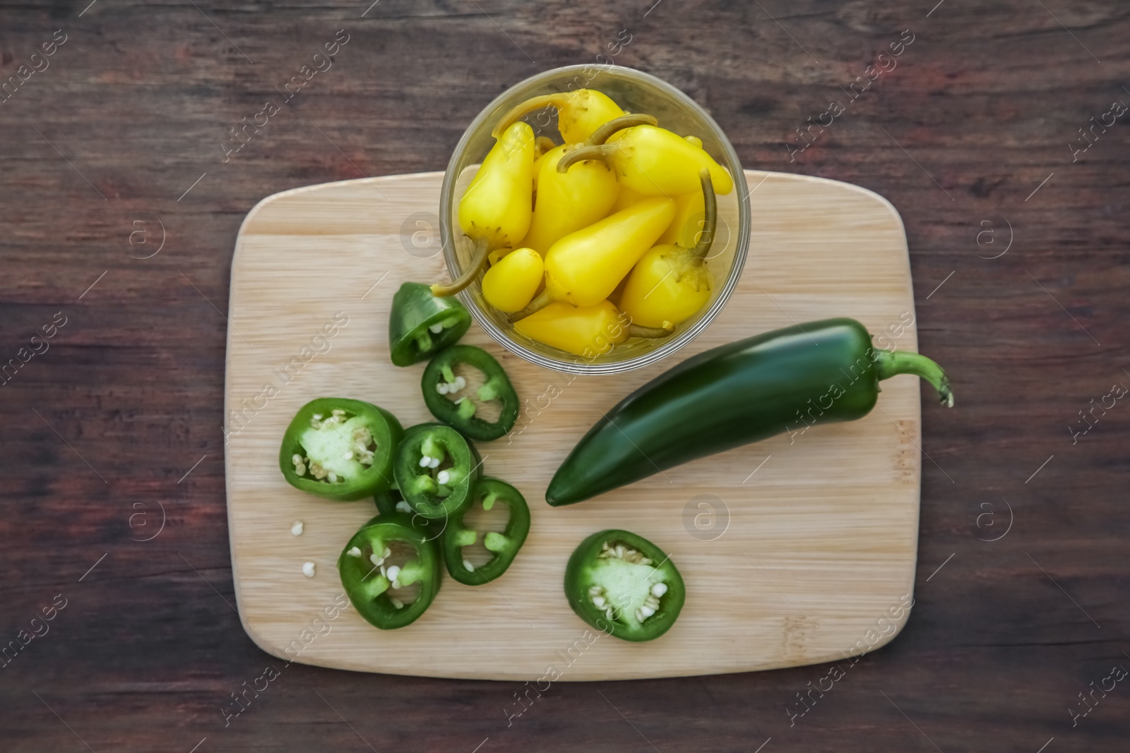 Photo of Fresh and pickled jalapeno peppers on wooden table, top view