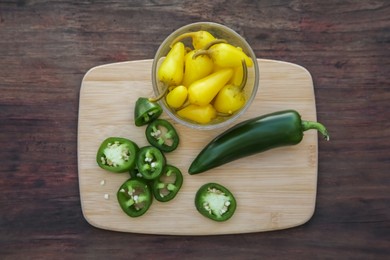 Fresh and pickled jalapeno peppers on wooden table, top view